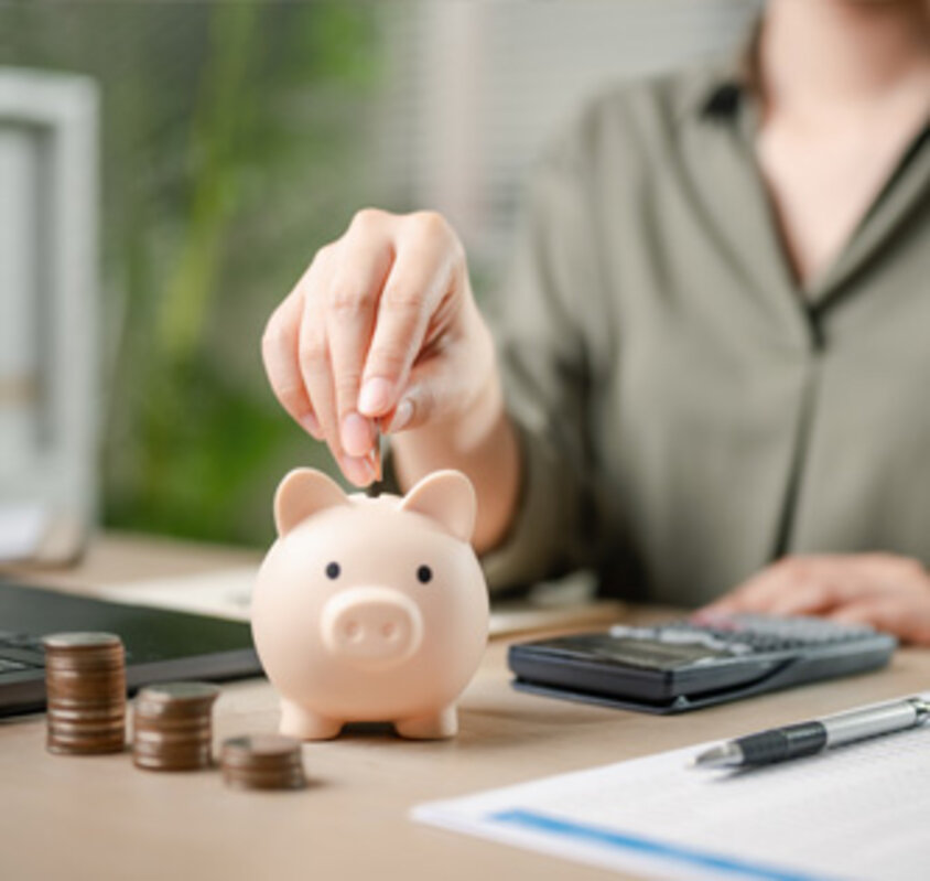Stockfoto, Frau gibt Geld in Sparschwein